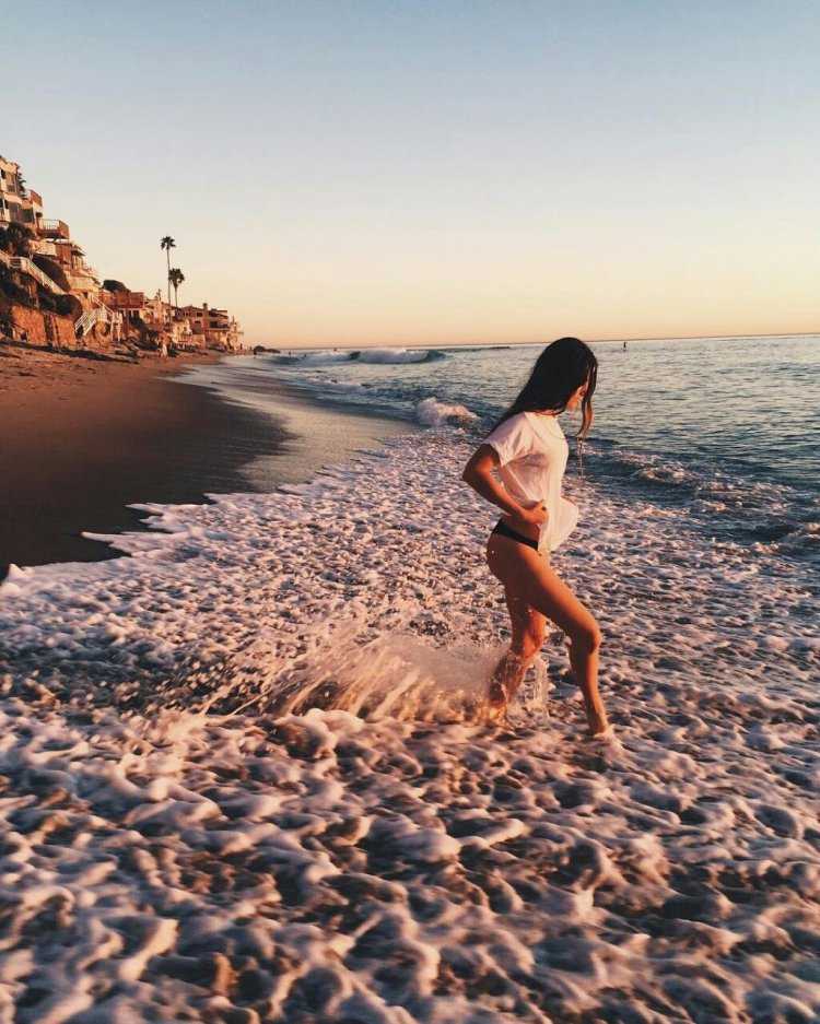 Брюнетка на пляже со спины