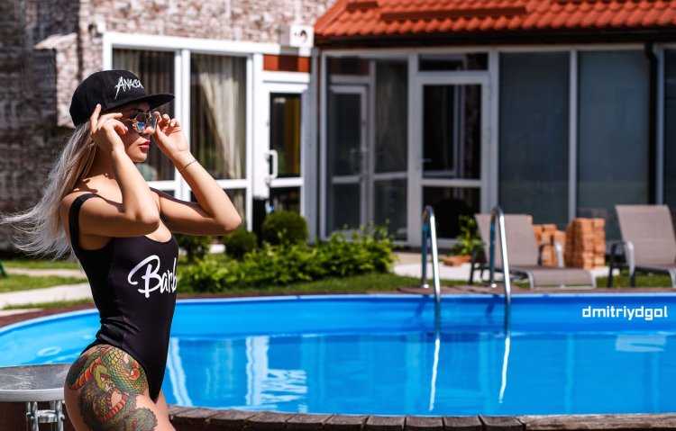 Обворожительная девушка с татуировкой расслабляется у бассейна