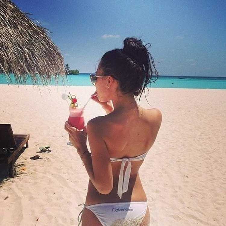 Брюнетка с коктейлем на пляже