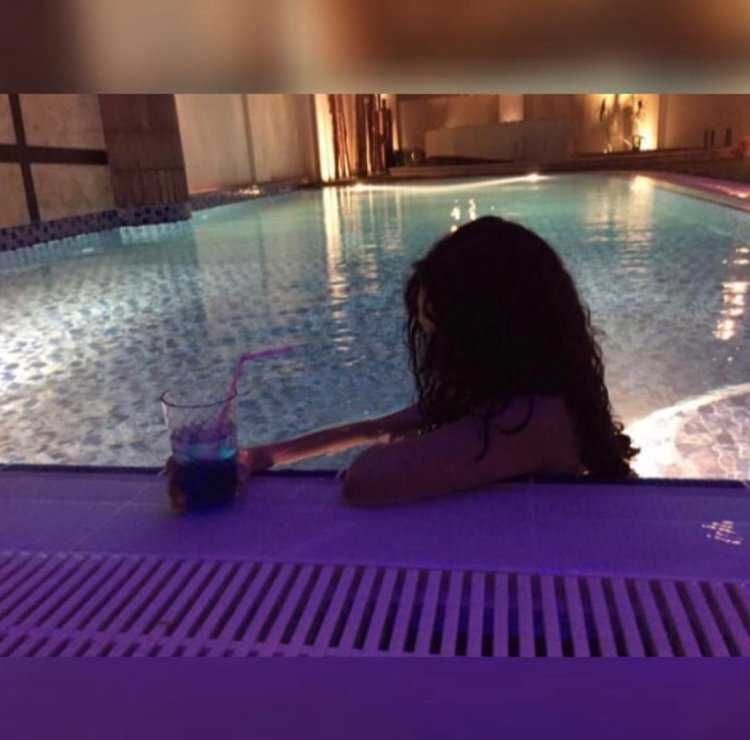 Брюнетка в бассейне со спины