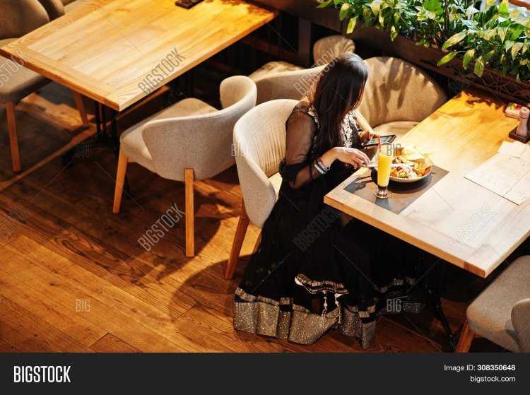 Девушка сидит в ресторане без лица