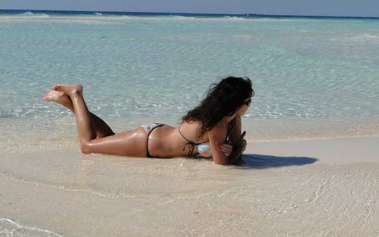 Брюнетка загорает на пляже